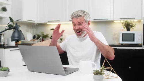 Man Working on Laptop at Home Gets Good News
