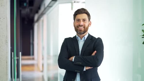 Smiling Businessman with Arms Crossed in Bright Office