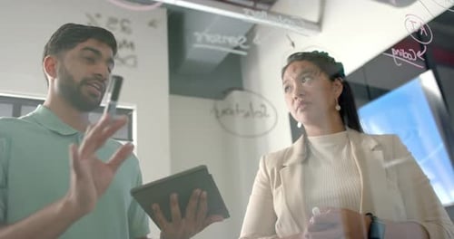 Discussing project, colleagues collaborating in office using tablet and whiteboard