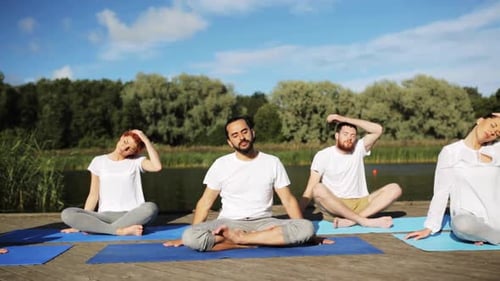 Group Doing Yoga Poses Outdoors on Wooden Dock