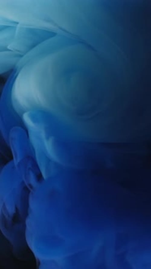 Swirling blue ink drops into a clear liquid