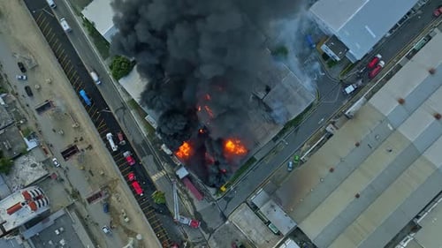Des flammes brûlent un bâtiment dans un parc industriel. Vue aérienne de haut en bas