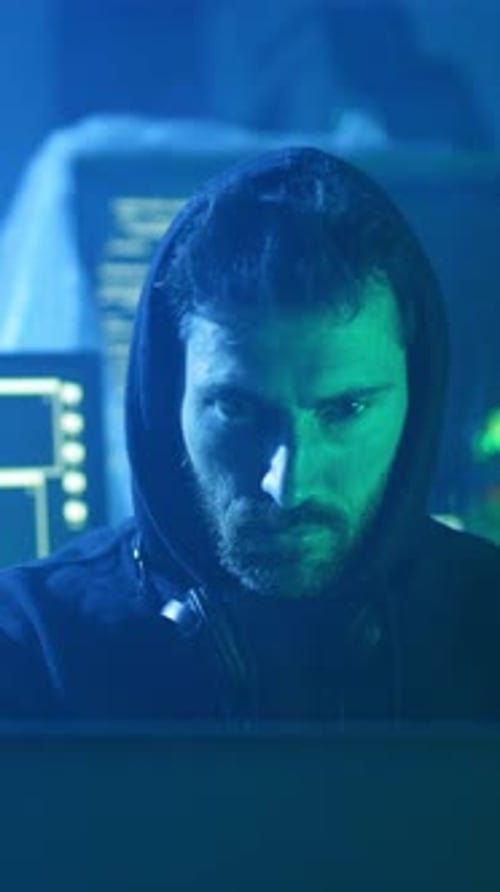 Ein Mann, der einen Hoodie trägt, schaut aufmerksam auf einen Computerbildschirm