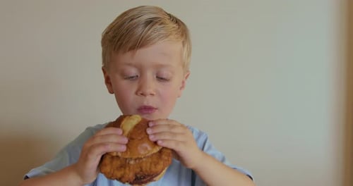 Blond Boy Eating Sandwich in a Bright Room
