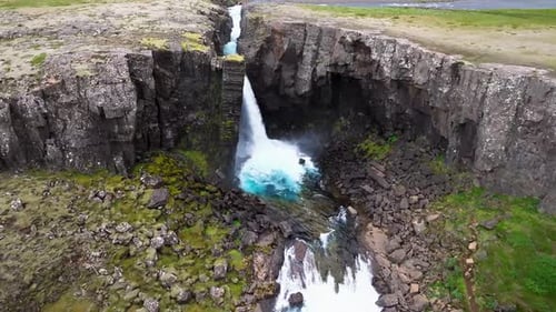 Aerial view of waterfall cascading in canyon, Iceland.