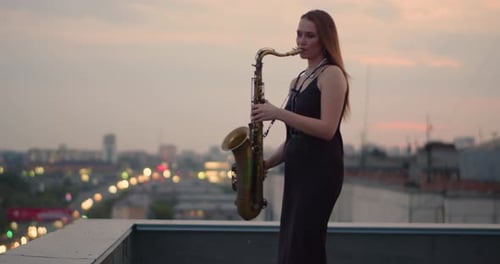 Woman Plays Saxophone on City Rooftop at Sunset