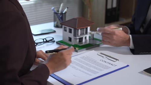 Client Is Signing A Real Estate Contract While A Realtor Is Explaining The Details Of The Agreement