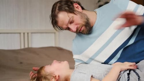 Man playing with his child on the bed