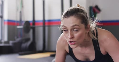 Close up video of determined caucasian woman doing push ups working out at a gym