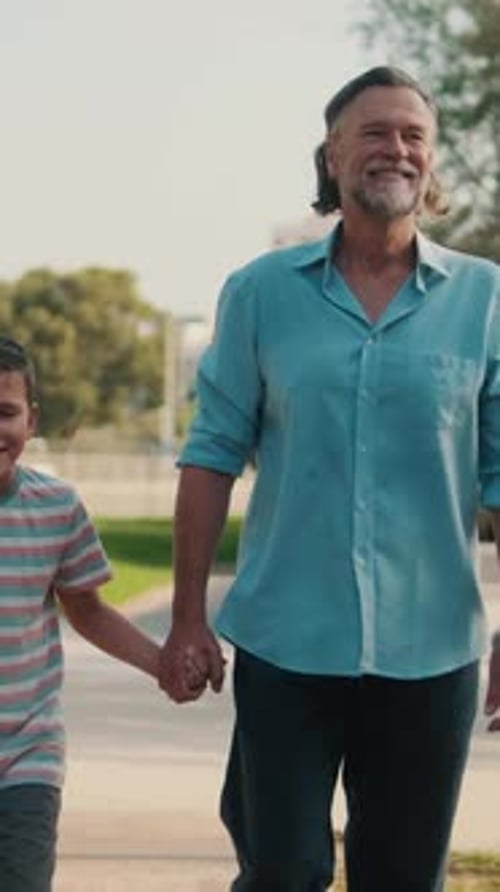 Vertical video, Grandfather And Grandson Walking In The Park