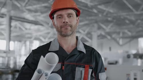 Engineer Planning Manufacture Work. Male Inspection Person in Protective Hardhat Wear. Blueprint
