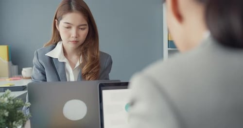 Asia businesswomen using laptop on table working and communicate sitting on office desk.