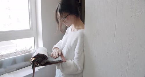 Woman Examining Fabric Samples by Window