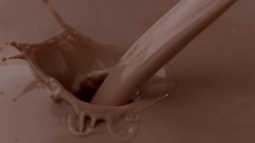 Delicious chocolate milk pouring and splashing in slow motion