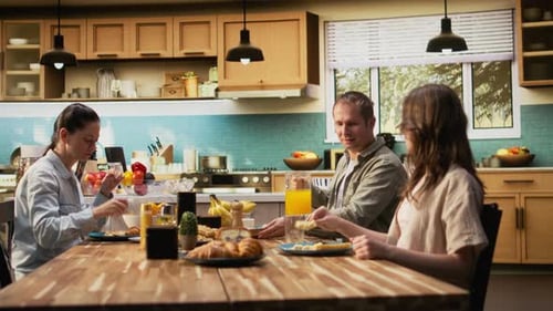 Parents and Kids Sitting Together at Breakfast Table Being Served By the Mother