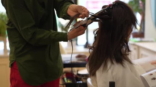 Male hairdresser ironing a woman's hair