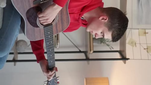 Young Adult Plays Acoustic Guitar in Living Room