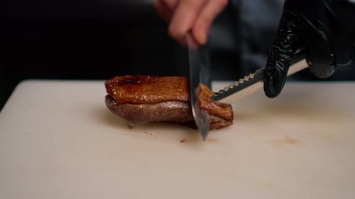 Professional restaurant kitchen chef cuts delicious roasted duck breast with a knife asian cuisine