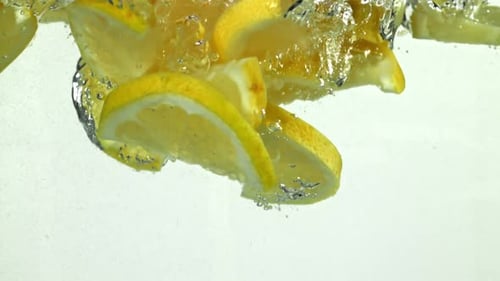 Lemon Slices Falling into Water with Bubbles