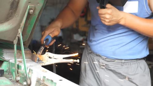 Male Hand of Adult Automaster Welds Metal Parts of Old Car with Welding Machine in Garage Arm of