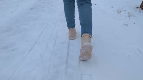 Woman Walking in Snow with Boots on Path
