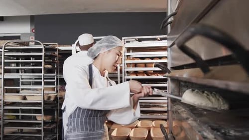 Verschiedene Bäcker arbeiten in der Backküche und legen Brot in Zeitlupe in den Ofen