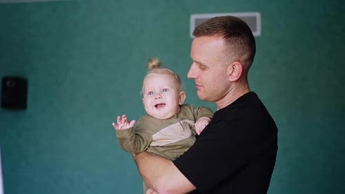 Father Holding Smiling Infant Indoors
