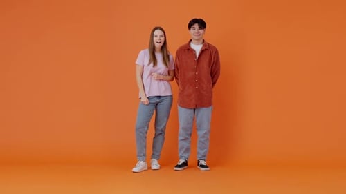 Smiling Asian Man and Woman Show Thumbs Up in Orange Room