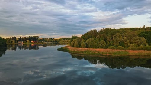Top Aerial Drone View of Calm Forest Lake at Sunset Clouds Sky Reflected in the Water Near Village