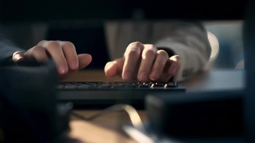 Nahaufnahme eines Arbeiters, der in einem Büro auf einer Tastatur tippt