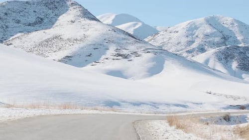 Fahren auf einer Bergstraße im Winter vor dem Hintergrund schneebedeckter Berggipfel
