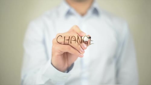Man Writes the Word Change on Clear Surface
