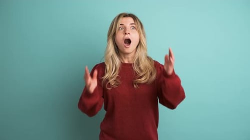 Stunned Young Woman with Opened Mouth in Blue Studio