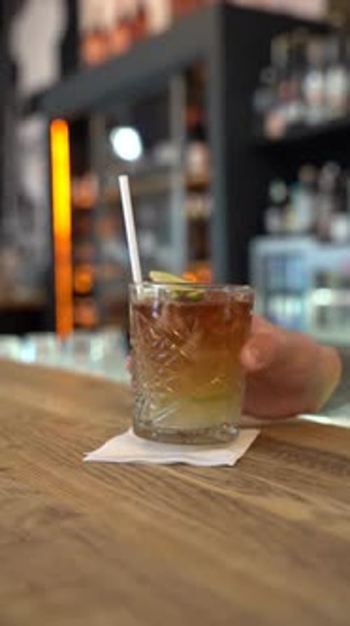Vertical shot of a Dark and Stormy cocktail with lime garnish on bar counter