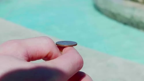 Close up shot of hand flipping coins into fountain. lucky myth illustration.