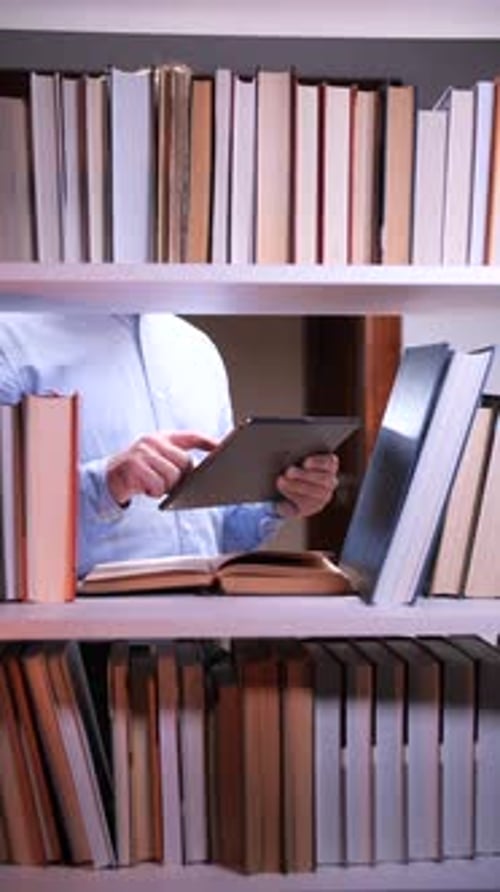 Vertical Video Professor Using Tablet and Consulting Book in Library