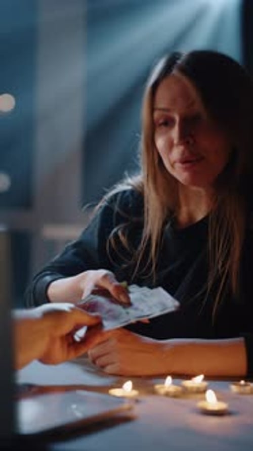 Woman Counting Money By Candlelight Indoors at Night
