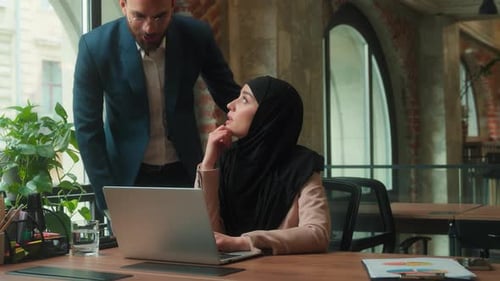 Woman Working on Laptop Discussing Project with Colleague