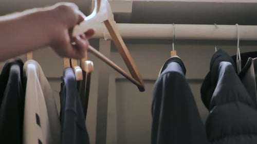 Hand places empty hanger in closet