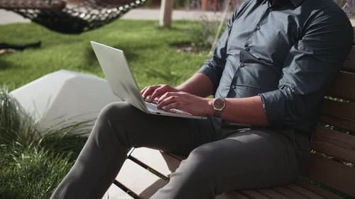 a man with a laptop in a park against a backdrop of green grass