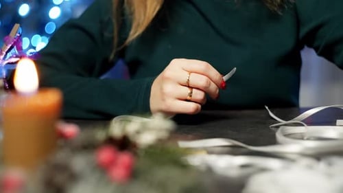 Woman Crafts a Snowflake Ornament with Ribbon at Table