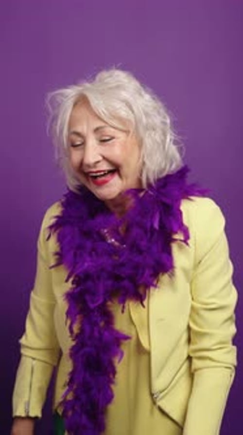 Playful Senior Woman Dancing with Purple Pom Pom