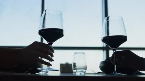 Les mains font tinter des verres à vin dans un restaurant