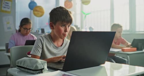 Computer Science Lesson Primary School Boy Sitting at Desk Using Laptop in Classroom