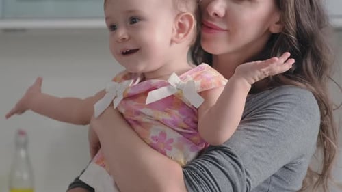 Cute Baby Girl Clapping Hands while Happy Young Mother Playing with Her