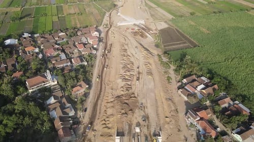 Vue aérienne de la construction de l'autoroute. Un camion à benne basculante passe devant le bâtiment.