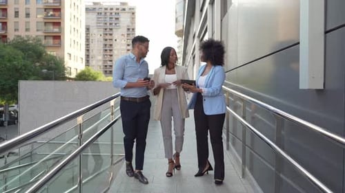 Video of diverse group of business colleagues walking and talking outside office in urban setting
