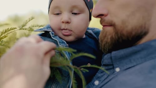 Loving Father Holding Smiling Baby Boy in Peaceful Park Setting