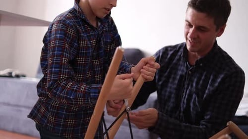 Father and Son Assemble Furniture From Small Parts Little Boy Helps His Father to Assemble a Chair