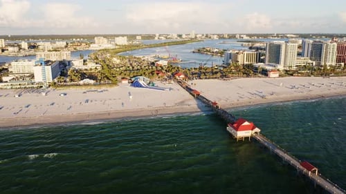 Long pier extending into ocean with beachfront hotels — aerial perspective
